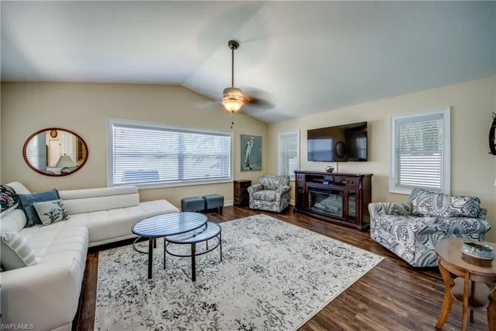 Living room featuring dark hardwood / wood-style flooring, ceiling fan, and lofted ceiling