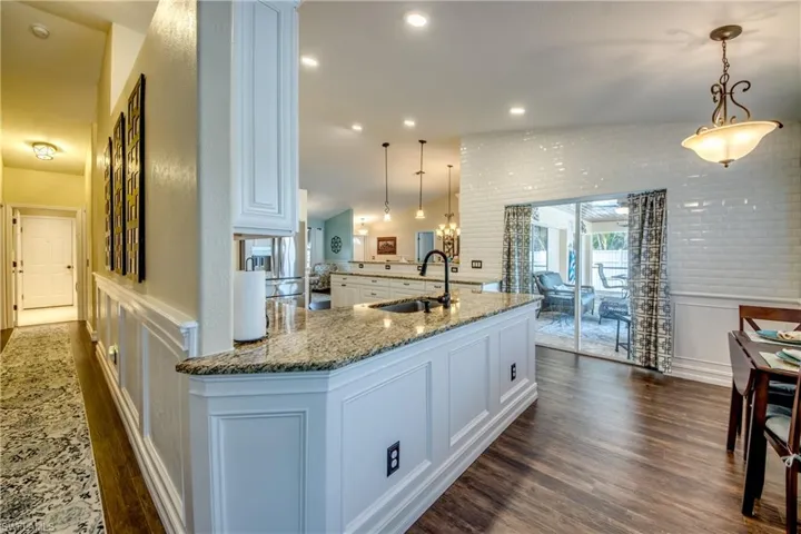 Kitchen with decorative light fixtures, sink, vaulted ceiling, and dark hardwood / wood-style flooring