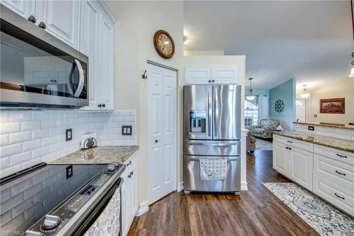 Kitchen featuring stainless steel appliances, white cabinetry, dark hardwood / wood-style flooring, and backsplash