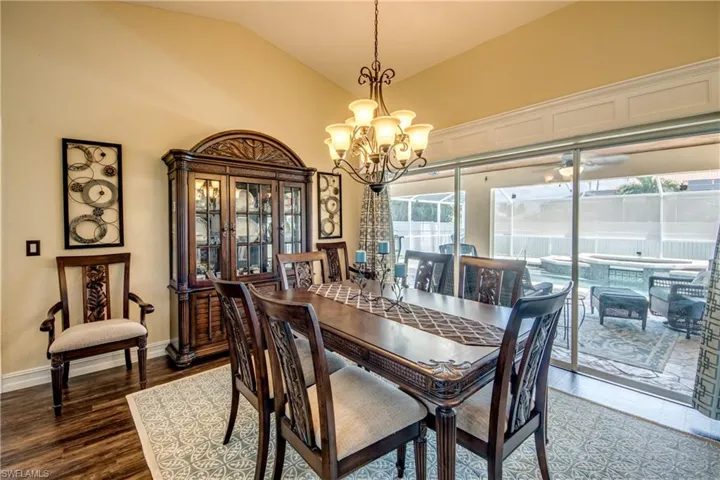 Dining area featuring vaulted ceiling, an inviting chandelier, and dark wood-type flooring
