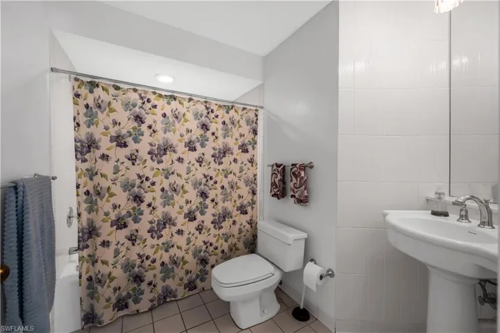 Bathroom with tile walls, light tile patterned floors, and shower / bath combination with curtain