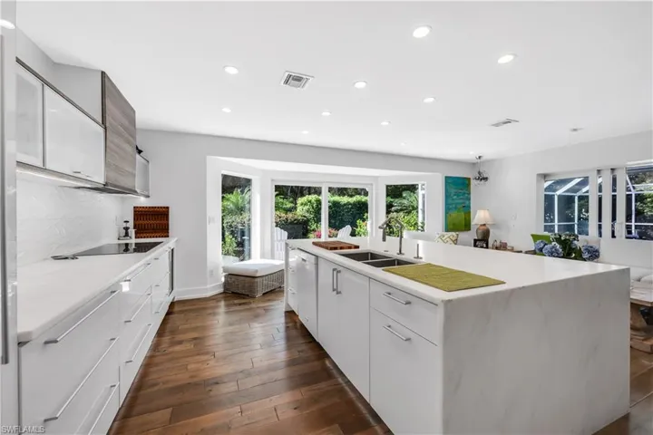 Kitchen featuring an island with sink, recessed lighting, modern cabinets, dark wood-type flooring, and light stone countertops