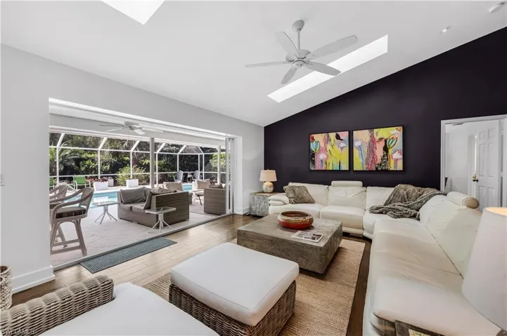 Great room with a sunroom, ceiling fan, wood finished floors, and lofted ceiling
