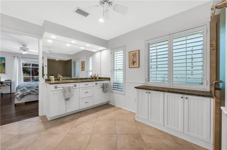 Bathroom with ensuite bath, double vanity, a ceiling fan, wainscoting, and recessed lighting
