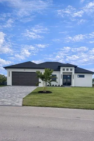 View of front of house featuring stucco siding, decorative driveway, a front yard, and an attached garage
