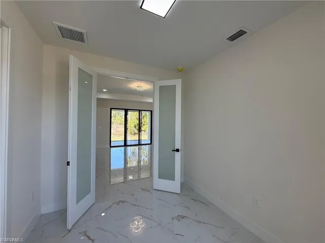 Spare room with french doors and light marble finish flooring