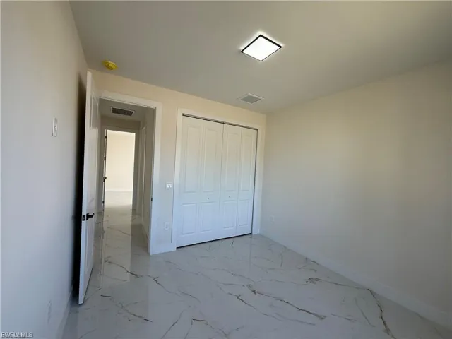 Unfurnished bedroom featuring a closet and light marble finish flooring