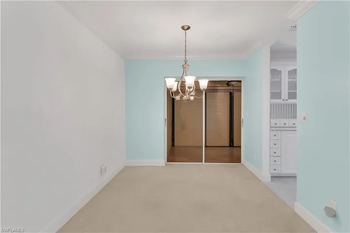 Unfurnished dining area with a chandelier, light colored carpet, and crown molding