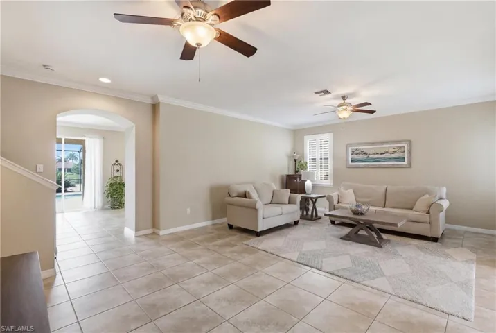 Spacious living area featuring neutral wall tones, tile flooring, and crown molding