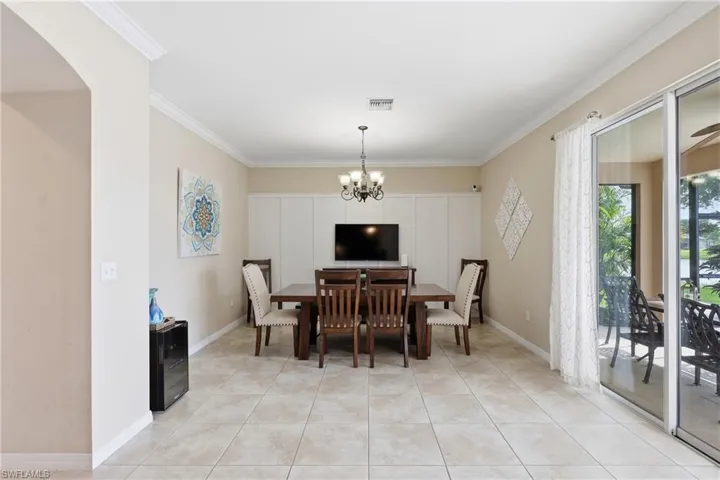 Dining area featuring tile flooring, crown molding, a built-in storage unit, and sliding glass doors opening to an outdoor patio with water views