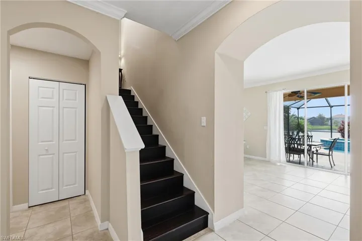 Foyer featuring a dark wood-finish staircase with white handrail, an arched doorway, and neutral wall paint