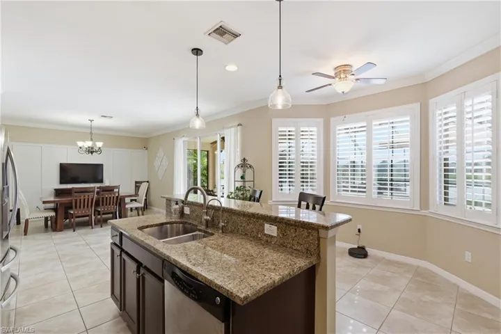 Kitchen featuring granite countertops, stainless steel sink, and dark wood cabinetry
