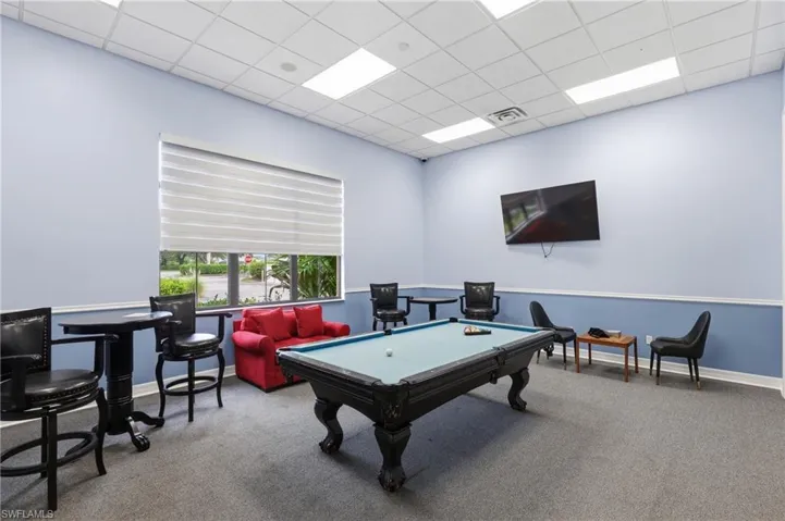 Recreational room featuring a billiard table, wall-mounted television, and a window with horizontal blinds