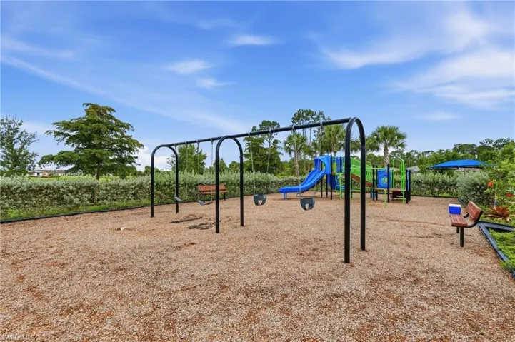 Outdoor recreational area featuring a swing set, multi-level play structure with a slide, and bench seating