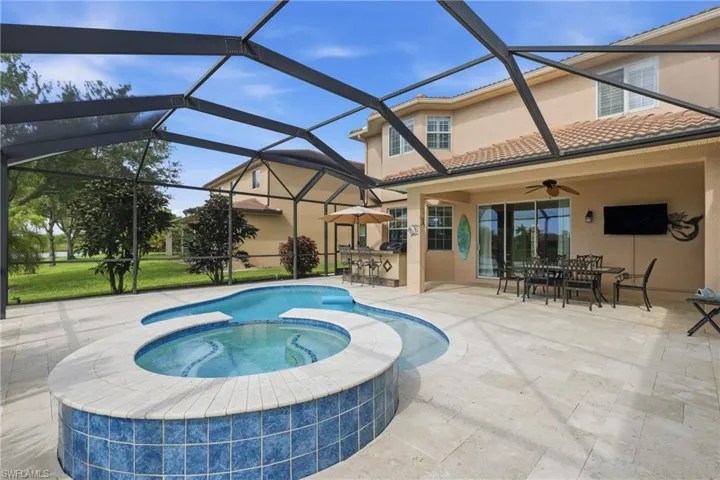 Screened outdoor living space featuring a custom-shaped pool and integrated spa with blue tile accents