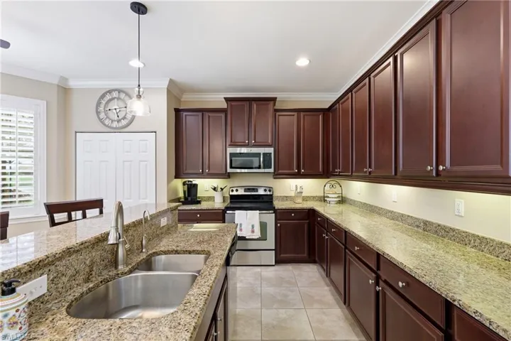 Kitchen featuring extensive wood cabinetry, granite countertops, stainless steel appliances, ceramic tile flooring, and recessed lighting