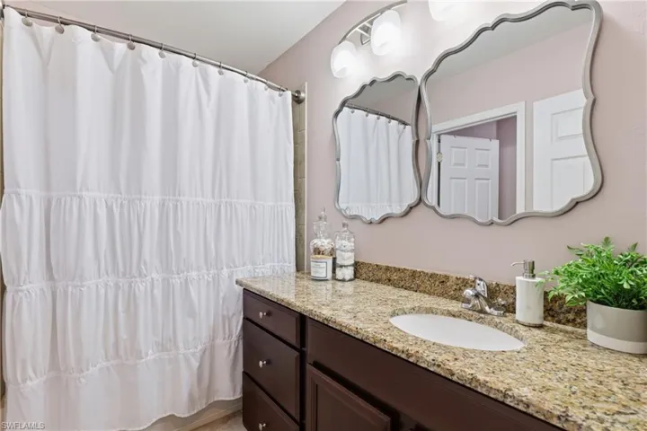 Bathroom featuring a spacious vanity with an undermount sink, granite countertop, and dark wood cabinetry