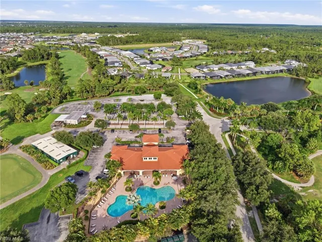 Expansive community featuring a clubhouse with a terracotta-tiled roof, a resort-style swimming pool, and surrounding green spaces