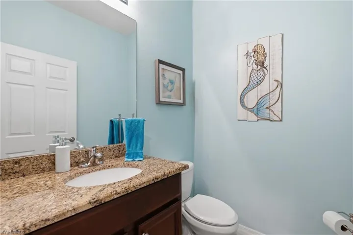 Bathroom vanity featuring a granite countertop with an undermount sink, chrome faucet, and dark wood-finish cabinetry