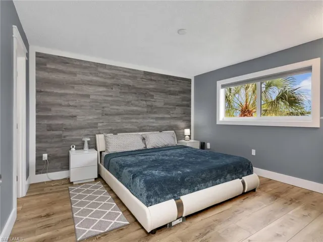 Wood-finish flooring, accent wall with horizontal paneling, ample natural light from a window, and recessed lighting