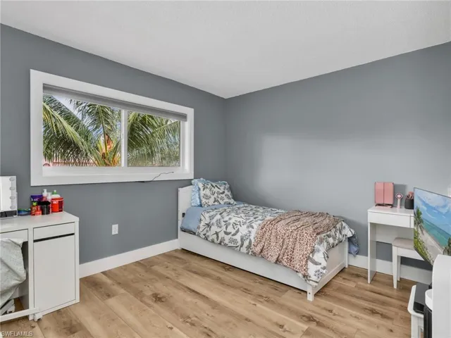 Wood-finish flooring, a wide window with white trim, and neutral wall tones
