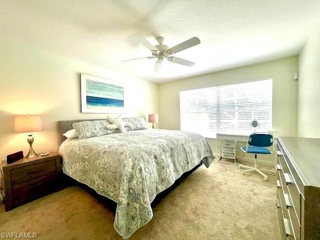 Carpeted bedroom featuring ceiling fan and a textured ceiling