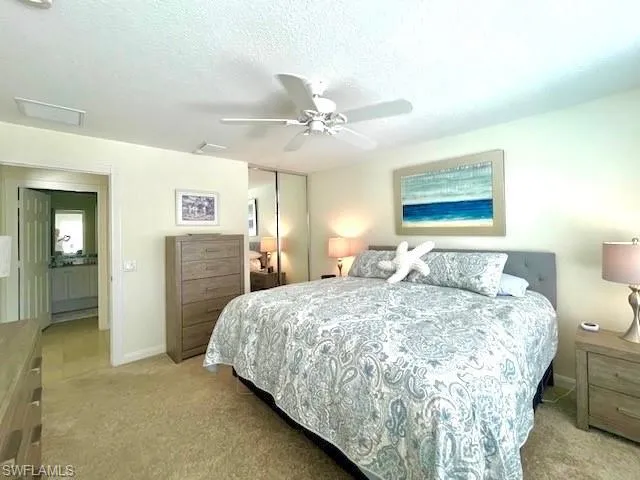 Bedroom featuring ceiling fan, light colored carpet, a closet, and a textured ceiling