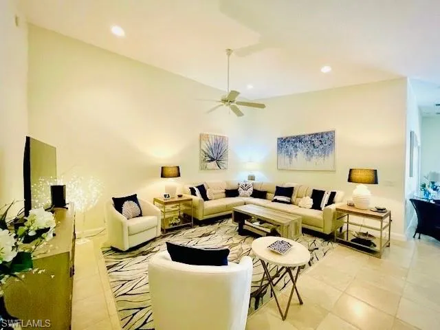 Tiled living room featuring ceiling fan and a high ceiling