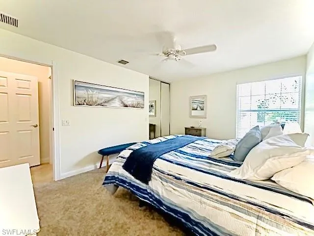 Bedroom with light colored carpet, ceiling fan, and a closet