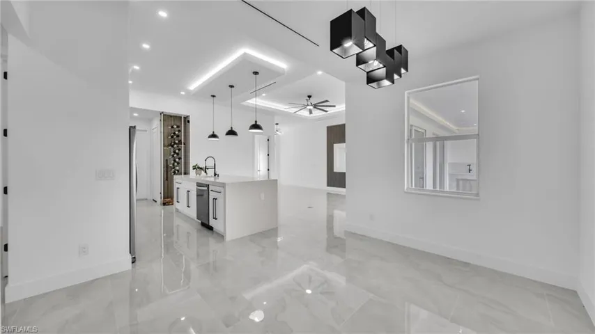 Kitchen with open floor plan, hanging light fixtures, light countertops, ceiling fan, and white cabinets