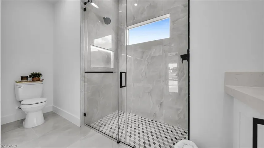 Bathroom featuring a marble finish shower and tile patterned flooring