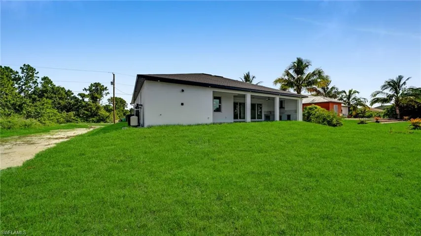 Back of house featuring a yard, stucco siding, and dirt driveway