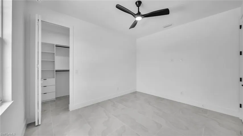 Unfurnished bedroom featuring a walk in closet and a ceiling fan