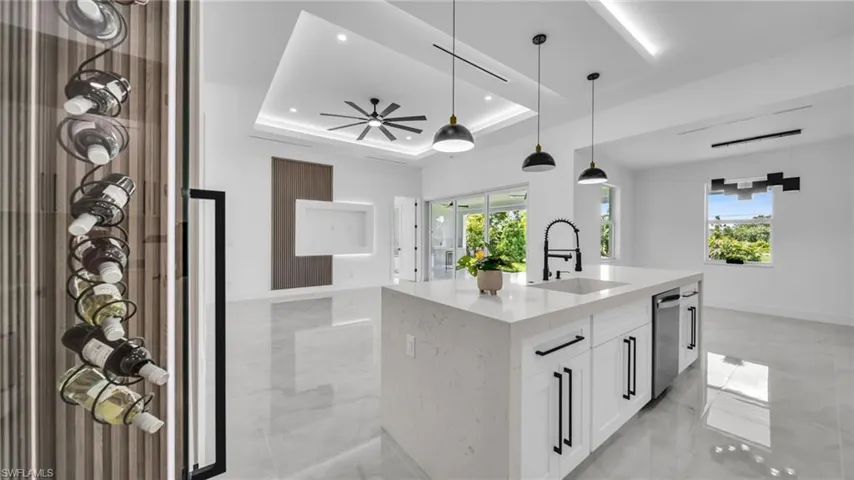Kitchen featuring a raised ceiling, plenty of natural light, pendant lighting, white cabinets, and recessed lighting