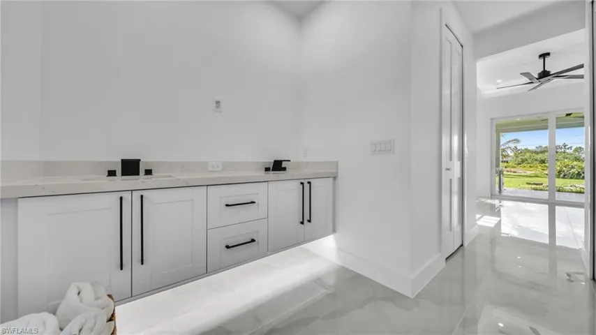 Bathroom with double vanity, a ceiling fan, and marble finish floors