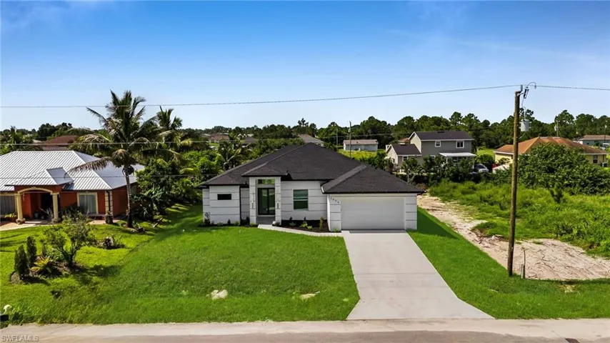 View of front of house with driveway, a front yard, a garage, and a residential view