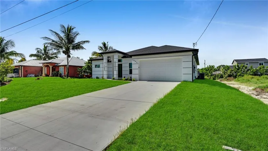 View of front of house featuring an attached garage, a front lawn, driveway, and stucco siding