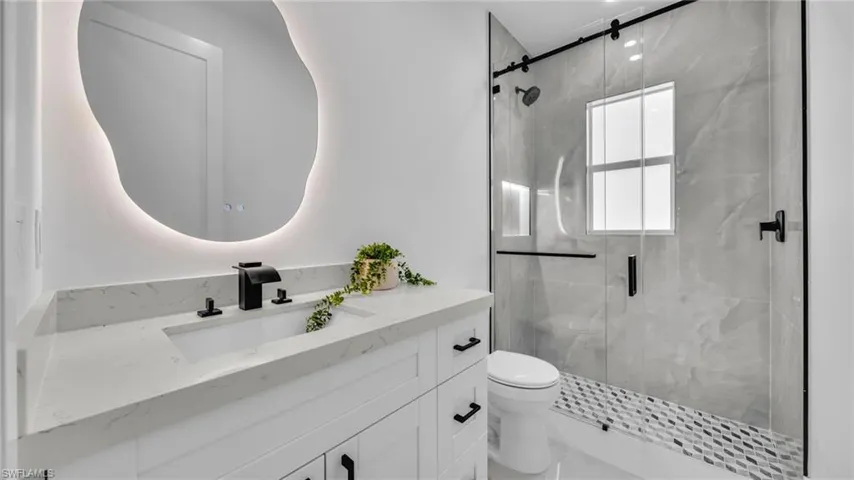 Bathroom featuring vanity and a marble finish shower