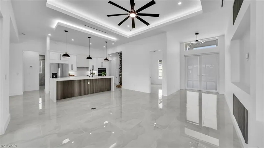 Unfurnished living room featuring light marble finish floors, a towering ceiling, french doors, ceiling fan, and a fireplace