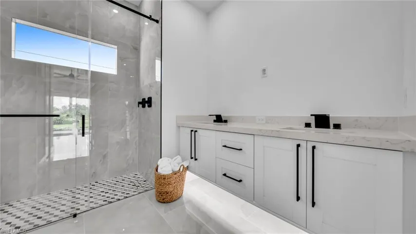 Bathroom with a marble finish shower, double vanity, and tile patterned floors