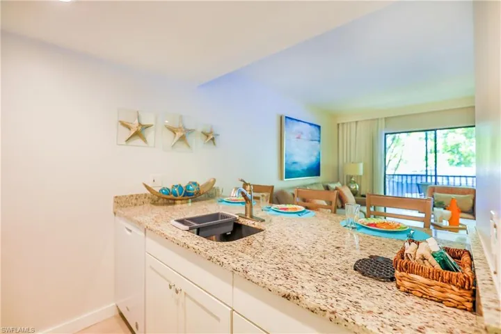 Kitchen featuring white cabinets, white dishwasher, light stone countertops, and a peninsula