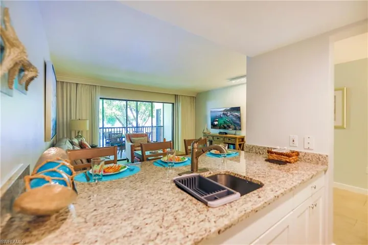Kitchen featuring light stone countertops, white cabinets, light wood-type flooring, a peninsula, and open floor plan