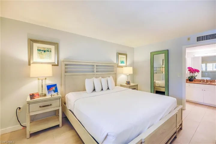 Bedroom with light tile patterned floors and connected bathroom