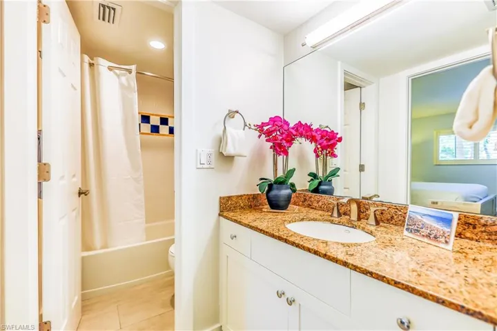 Bathroom with shower / bath combo with shower curtain, vanity, light tile patterned floors, and recessed lighting