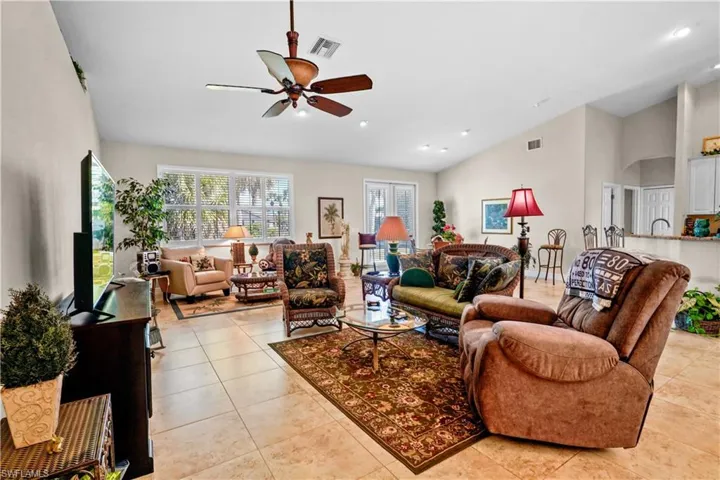 Great room serves mutlple uses. A wonderful gathering spot! The Lght patterned 20" porcelain tile floors, 5 3/4" baseboards, white wood plantation shutters on hurrican windows and doors, ceiling fan and , high vaulted ceiling, and recessed lighting.