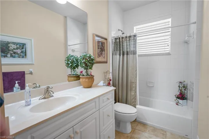Guest bathroom featuring shower/bath combo with tile to shower tile to the ceiling, linen closet, vanity with solid surface counter top, and 20" porcelian tile.