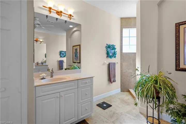 Full bath with vanity, light tile patterned flooring, walk in shower, and a ceiling fan