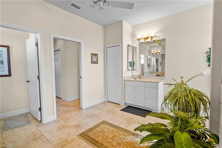 Bathroom with vanity, private water closet, a linen closet, and a ceiling fan two seperate vanities with solid surface wounter tops.