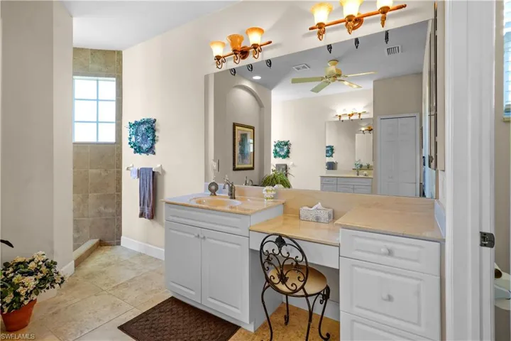 Full bathroom featuring vanity, light tile patterned floors, a ceiling fan, and tiled shower