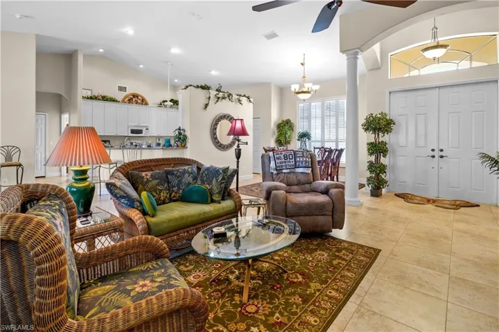 Living area with arched walkways, high vaulted ceiling, lightcolor 20" porcelain tile floors, decorative columns, and recessed lighting 5 3/4" baseboards.